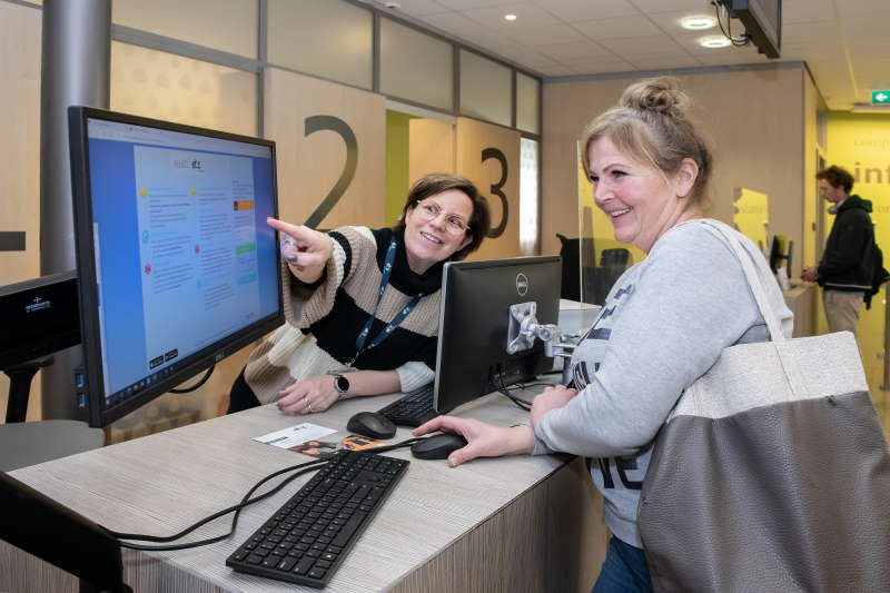 een bezoeker krijgt aan de balie uitleg over MijnETZ een bezoeker krijgt aan de balie uitleg over MijnETZ